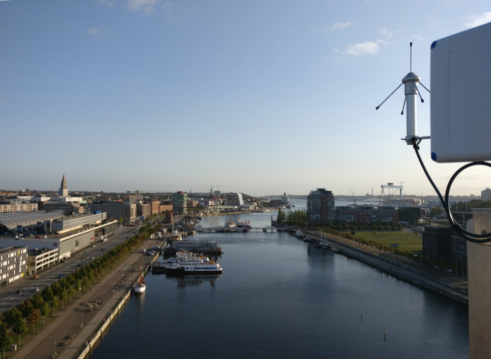 Canal y antena LoRaWAN en Kiel, Alemania, con visualización neón de sistema de sensores y tecnología de tratamiento de agua.